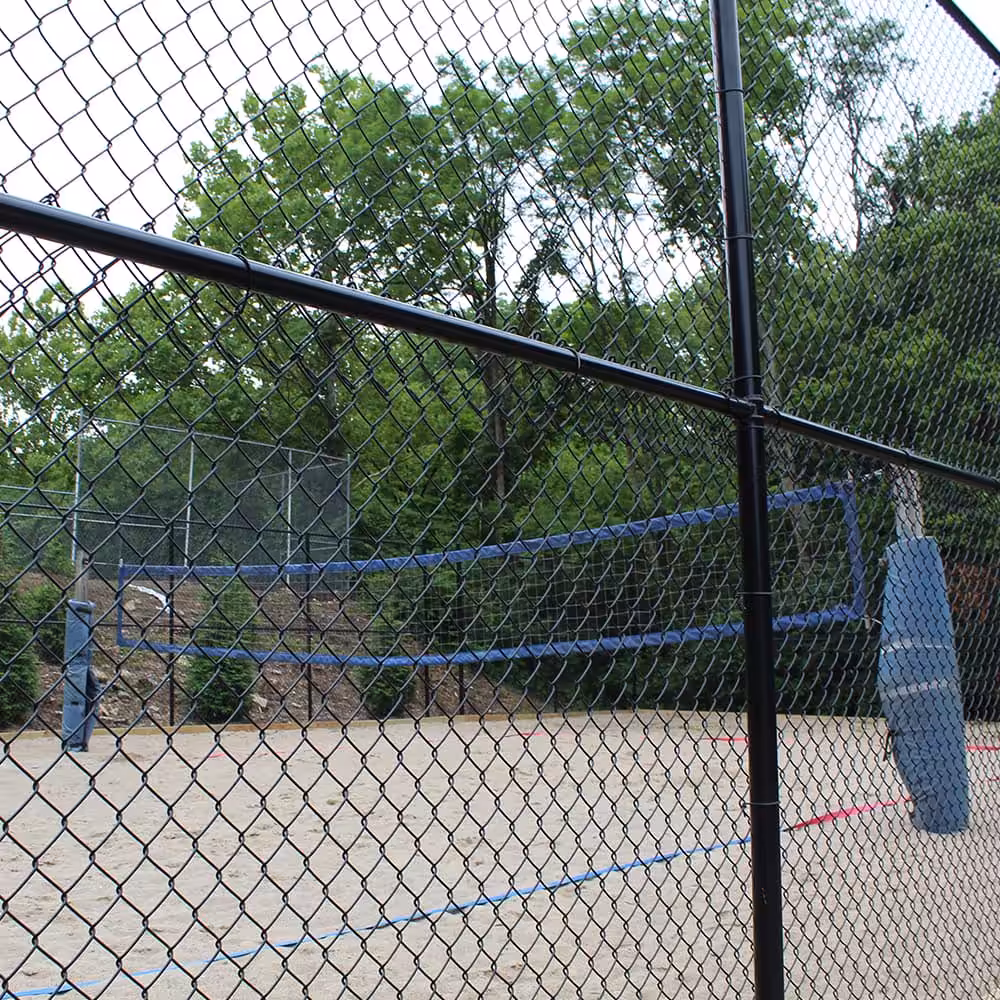 A chain link fence that surrounds sand volleyball