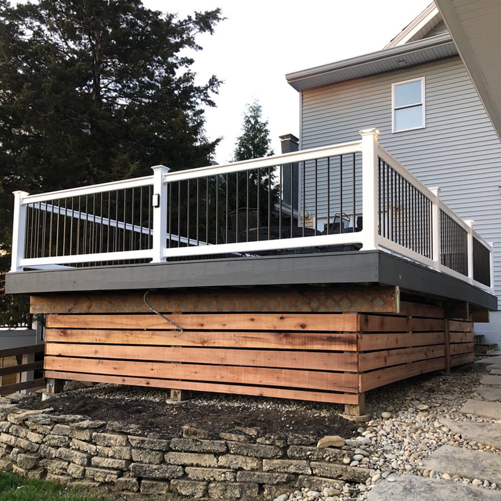 A backyard deck with white and back railings