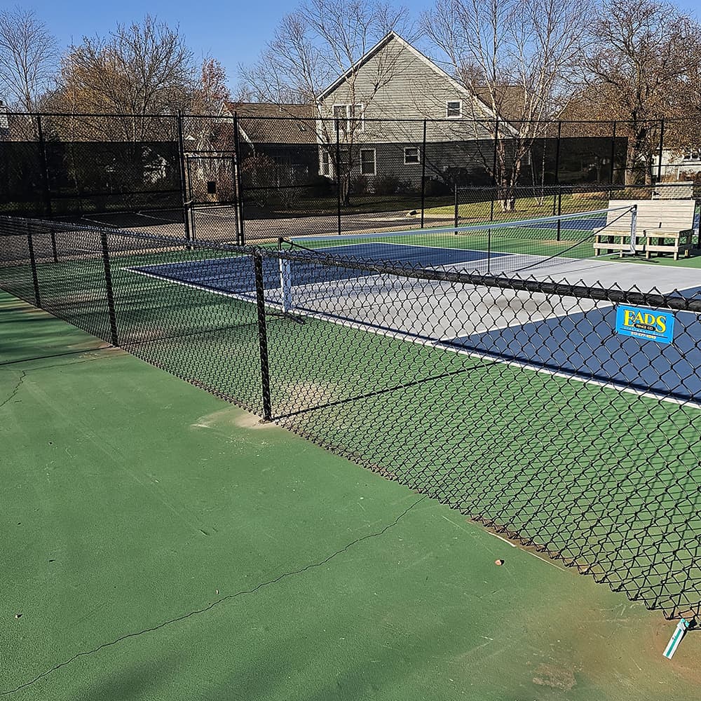 Two black fences around a pickle ball court
