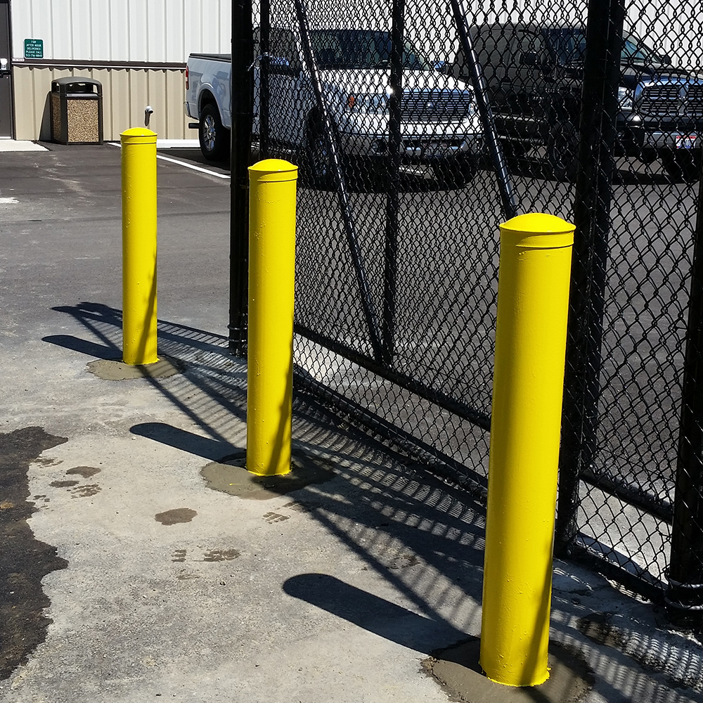Three yellow bumper posts in front of a chain link fence